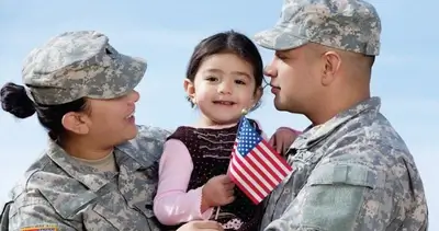 Little girl holds U.S. flag in arms of military parents