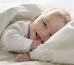 Baby lying on pillow giggling